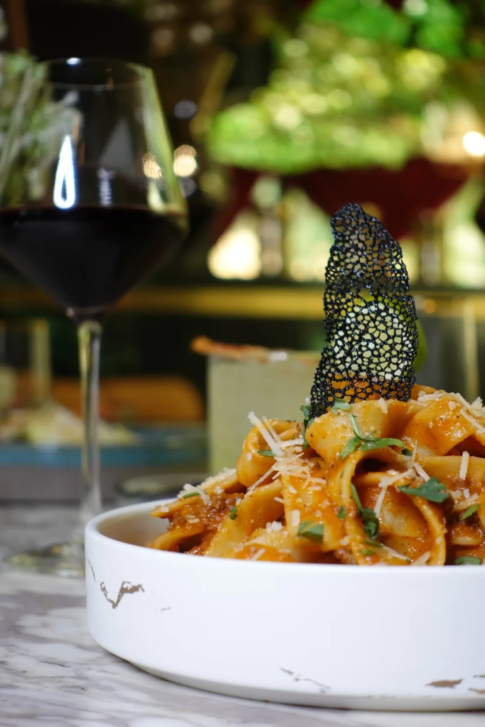 Plat signature de pâtes italiennes accompagné d'un verre de vin