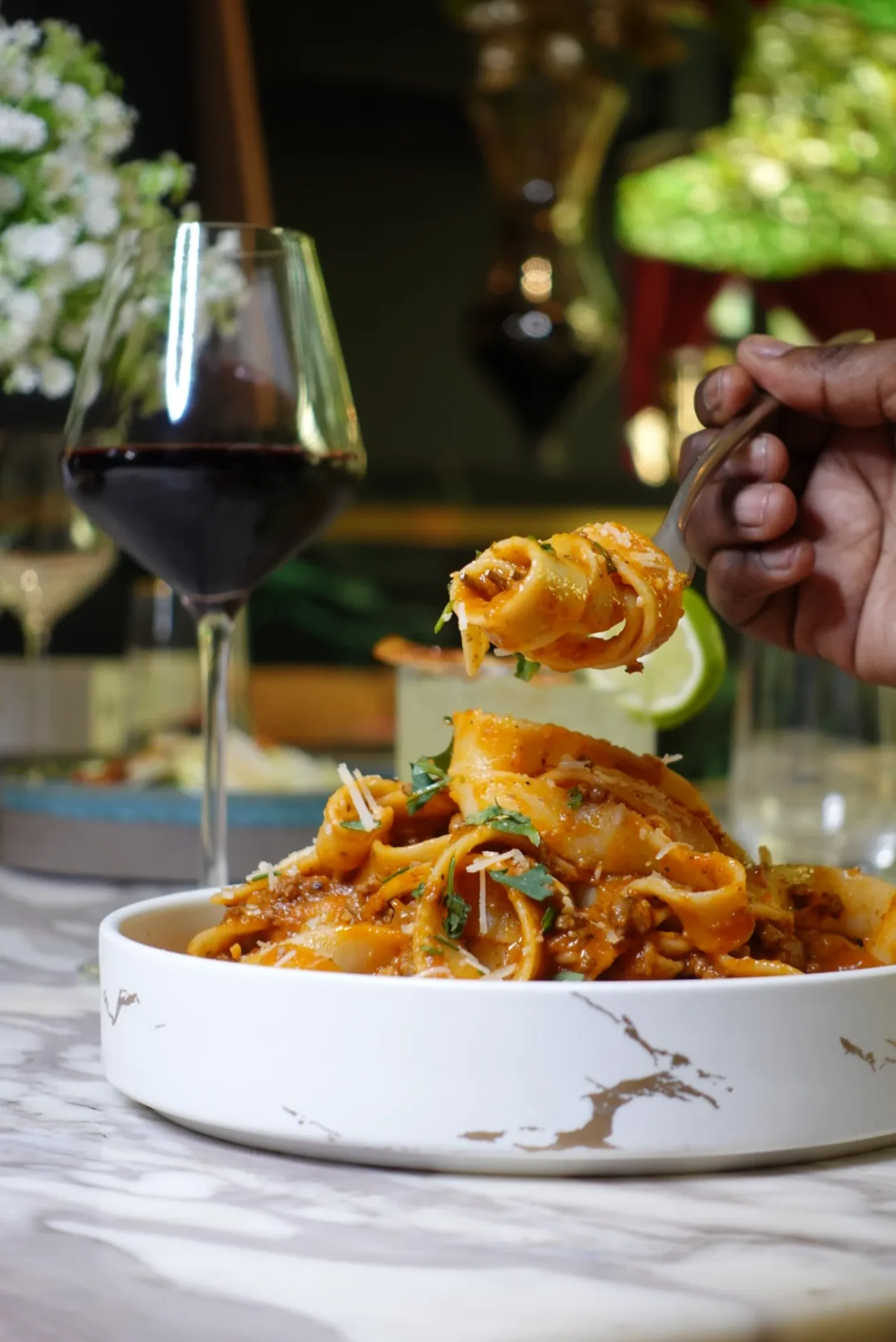 Plat signature de pâtes italiennes servi avec un verre de vin rouge